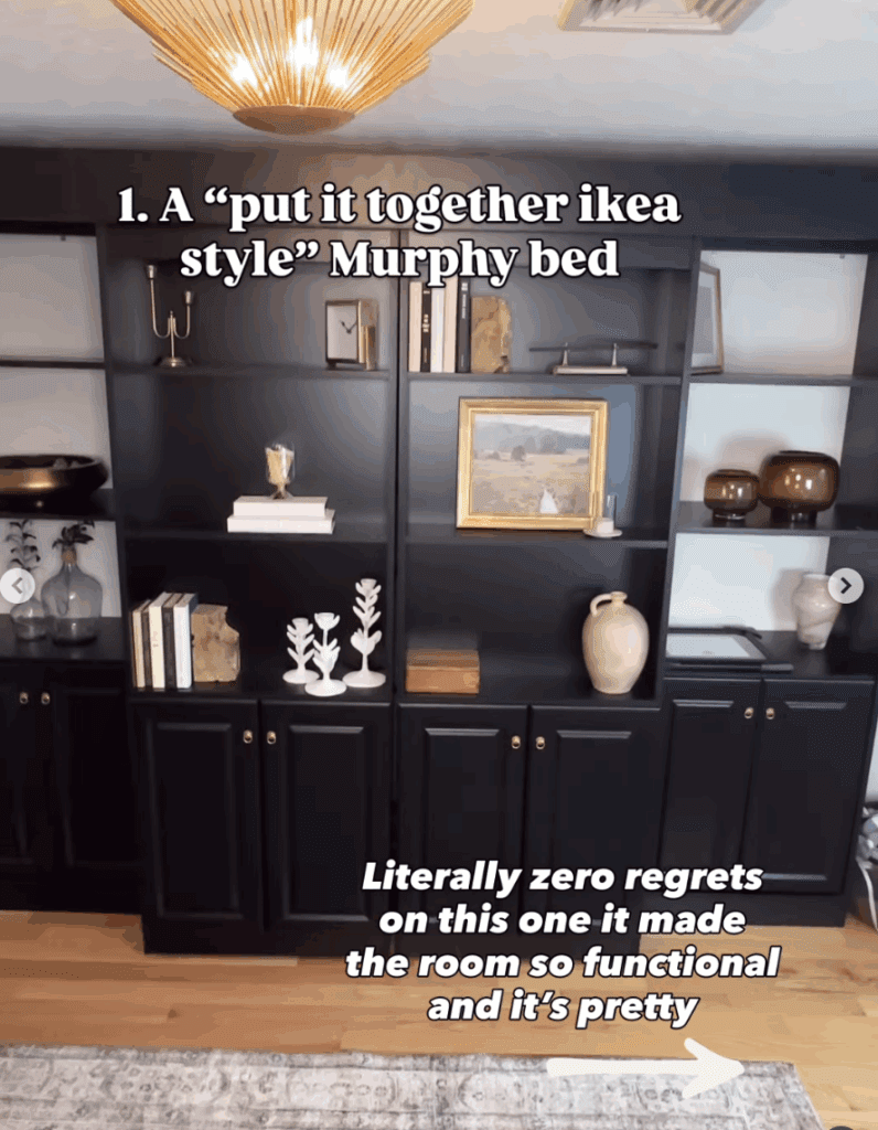 Black built-in Murphy bed closed, styled with modern gold light fixture, decorative books, vases, and framed art — functional and stylish guest room furniture solution.