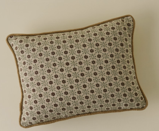Rectangular decorative pillow with a vintage-inspired geometric floral pattern in muted brown and green tones, finished with tan piping along the edges.