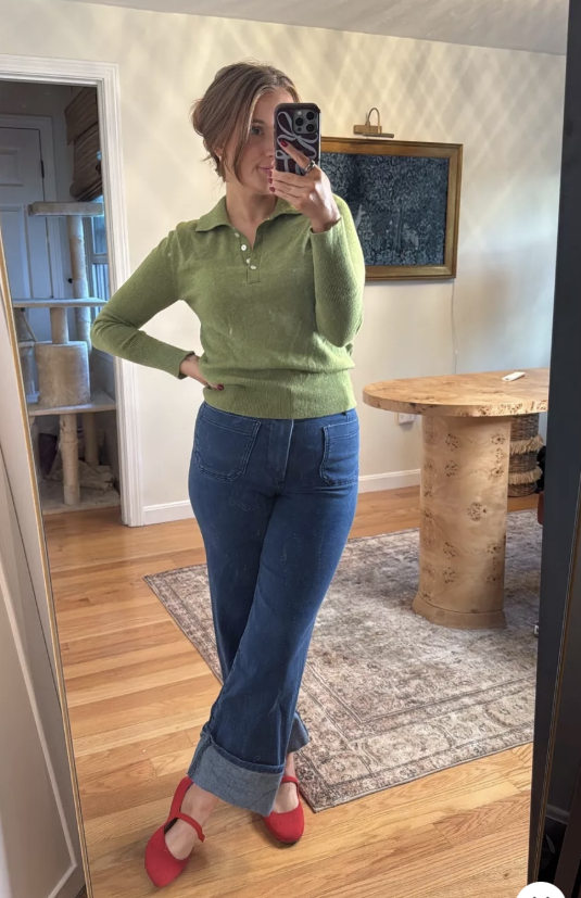 teaching outfit wearing a green cashmere sweater, dark wash wide leg jeans that are cuffed at the bottom and cherry red mary jane flats