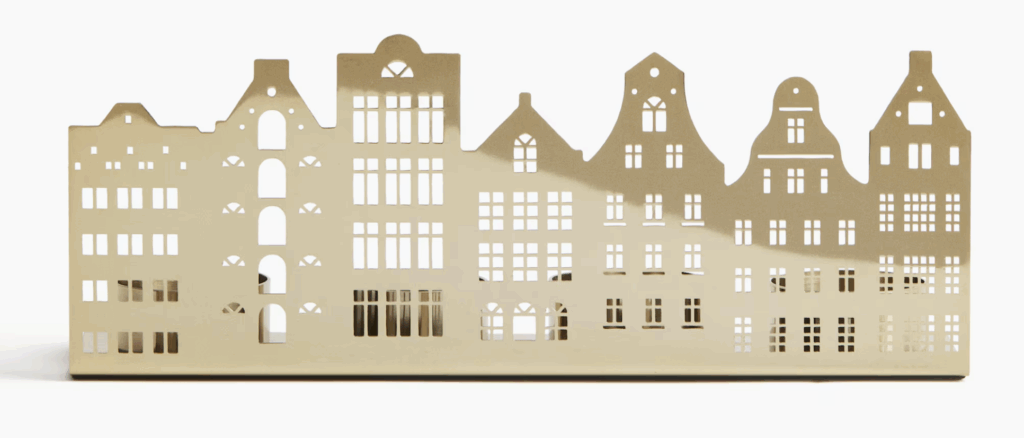 Gold metal multiple-house Christmas village candle holder from H&M Home, designed with cut-out building silhouettes for a glowing festive display when filled with tea lights. Gold Christmas Decor