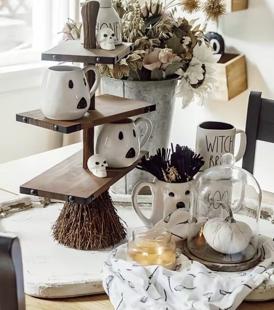 Witch broom tiered tray styled with ghost mugs and a mini skull for Halloween